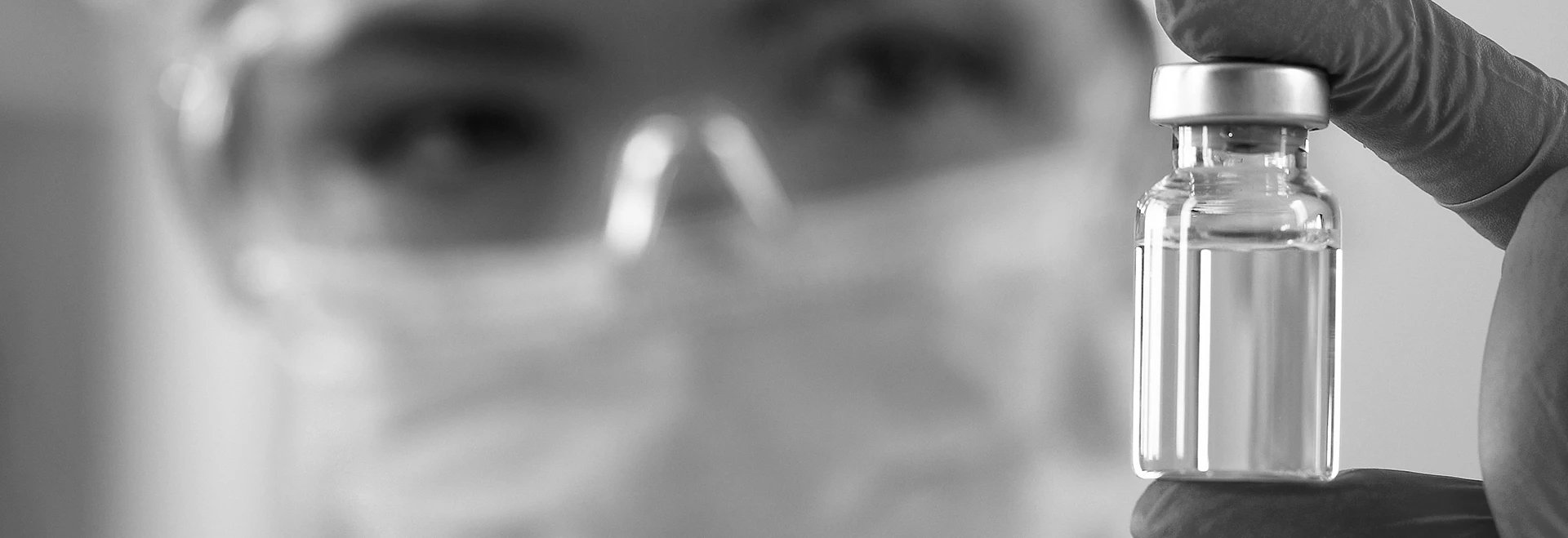 This photo is of a person in safety goggles and a mask lifting up a vile