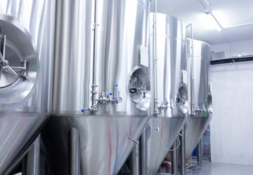 A picture of stainless steel tanks in a factory to be used for alcohol production