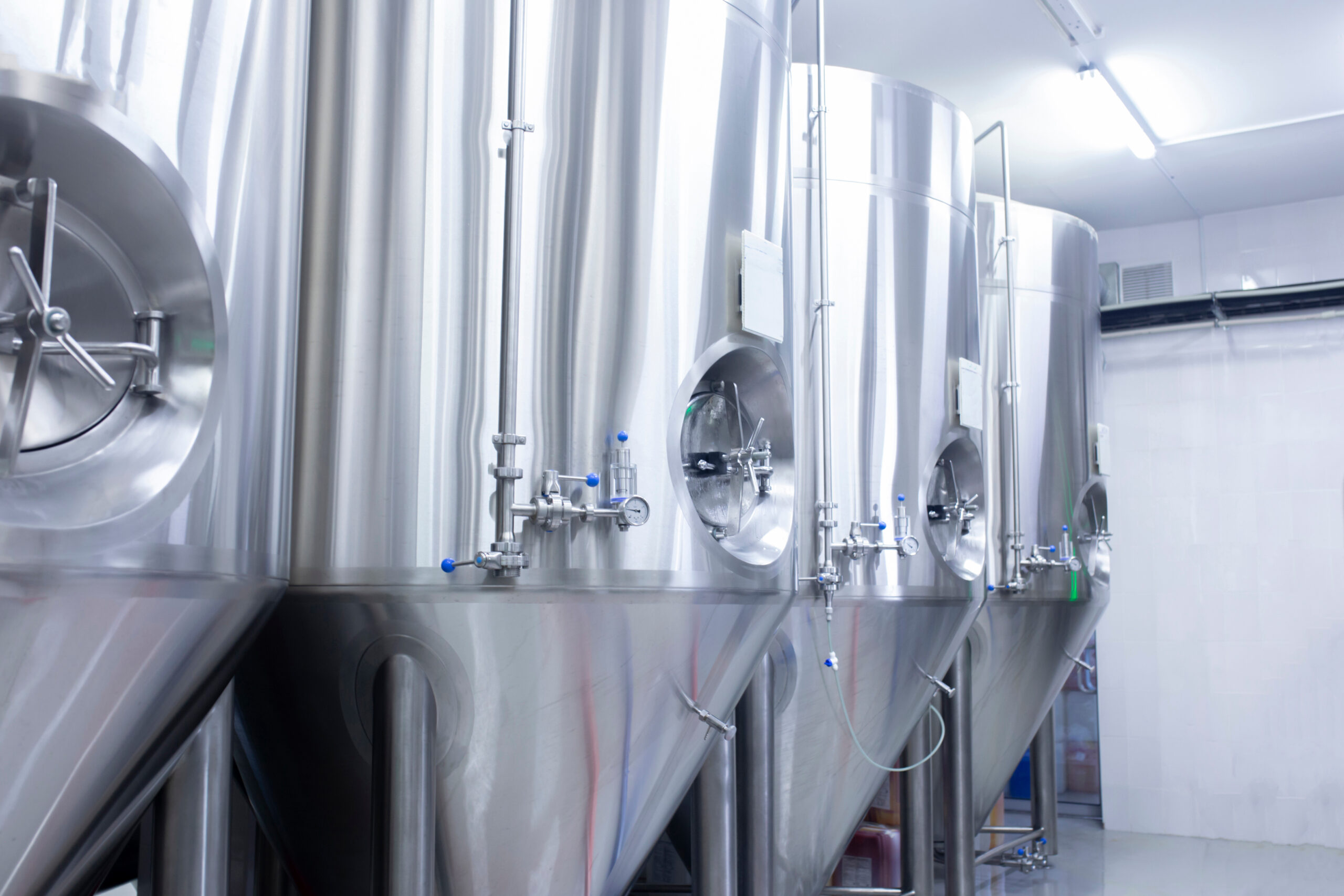 A picture of stainless steel tanks in a factory to be used for alcohol production
